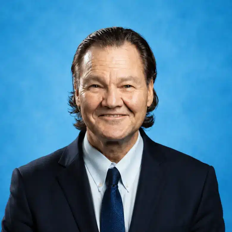 Headshot of Harry Gruenspan, MD, PhD with blue background