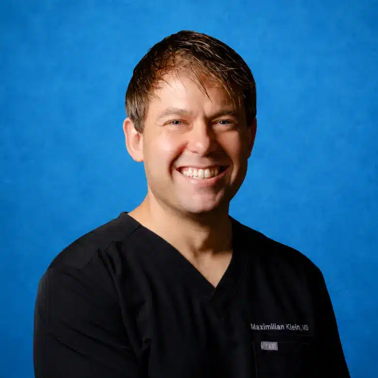 Headshot of Maximilian Klein, MD, FACOG with blue background